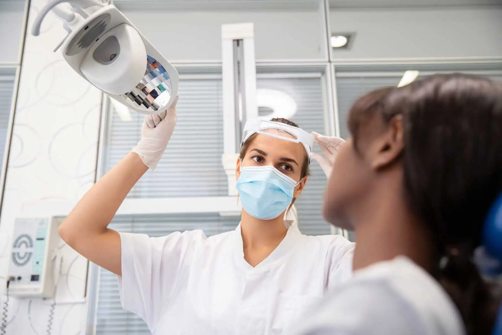 A Dental Hygenist adjusting the light above a patient.